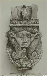 Carved female head with a tall headdress of cobras and spiral side locks, shown on a photo mount