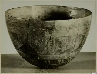 Faience bowl with pattern: a deep rounded bowl with bands of decoration and cracks running down its side.
