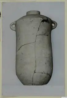 Cylindrical pottery vessel with a narrow neck and two small lug handles, cracked and mended, from Tomb 10 at Marion.