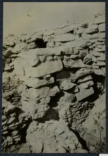 Stone wall remains on the Acropolis of Idalion, with gaps between the blocks, loose soil and scrub below.