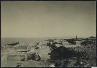 Ruins of Vouni Palace on a rocky headland, with stone walls and blocks and the sea beyond