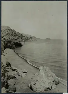 Rocky coastline with a sandy beach and calm sea at Vouni, with a small island offshore.
