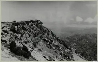 Rocky hilltop at Vouni with scrubby bushes, looking out over a valley of hills and terraced slopes.