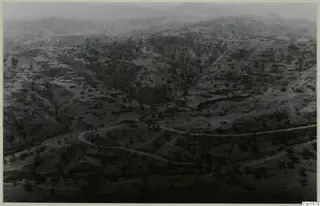 Wide view over hilly, wooded country with a winding road, taken from high above the palace site at Vouni.