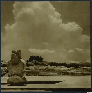 Stone steps, a rough stone object and a tree at Vouni palace under tall clouds