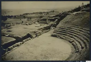 The theatre at Soli, with curved stone tiers of seating around a paved central area and the sea in the distance.