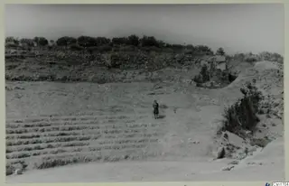 The theatre at Soli, with tiered rows of stone seating and one standing person