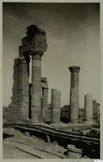 Standing stone columns and low wall ruins with a rail track in the foreground, captioned as North Africa