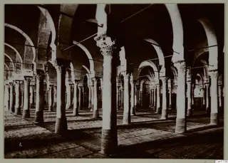Interior of a building with long rows of stone columns and arches, North Africa.