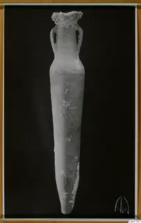 Tall pottery vessel with two loop handles and a pointed base, photographed upright against a black background