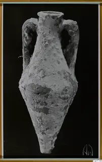 Two-handled vessel with a narrow neck and pointed base, its surface crusted, shown against a black background.
