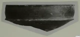 Pottery sherd with a rim and dark surface, mounted on grey card