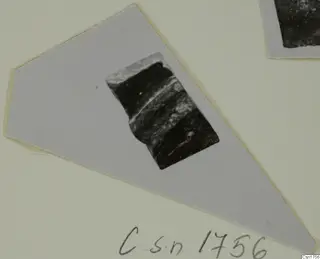 Dark pottery sherd with a ridged edge, shown on a pale grey mounted card, from the Roman Wares I-III group