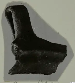 Broken pottery sherd with a tall, narrow projection rising from a thicker body fragment, shown on a grey card mount