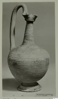 Pottery jug with a tall ribbed neck, flared mouth, strap handle and globular body, standing on a ring foot.