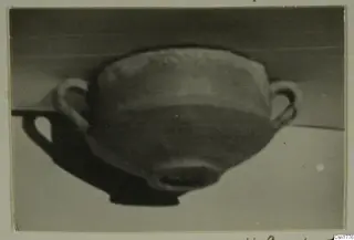 Two-handled bowl photographed at an angle on a pale surface