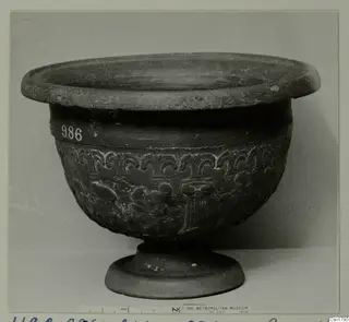 Footed bowl with a flaring rim and raised ornament around the body, photographed against a pale backdrop