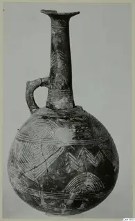 Red Polished III jug from Lapithos with a tall neck, single strap handle and linear patterns of arcs and chevrons on the body