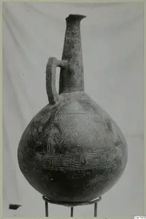 Red Polished III jug from Vounous with incised decoration, standing on a metal ring stand