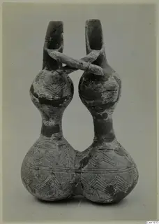 Pottery Red Polished III jug, double-spouted, with a bridge handle and incised chevron decoration