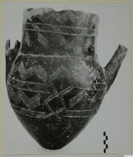 Red Polished I pottery jar with incised zigzag bands and two lugs, shown beside a scale bar