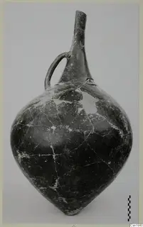 Pottery vessel from Vounous with a long neck and a single loop handle, photographed against a plain backdrop with a scale bar