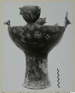 Pottery vessel from Vounous with a tall pedestal foot, incised zigzags and a small cup rising from its body