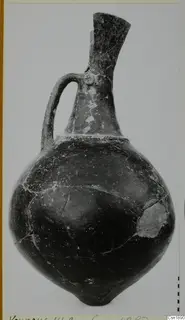 Black-polished jug with a tall flaring neck and a single loop handle, from Vounous.