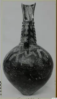 Dark-surfaced vessel with a tall flaring neck, two handles and incised zigzag and circle patterns on the body