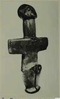 Dark metal-looking figurine from Petra tou Limniti with a rounded head and a horizontal bar across the body