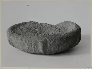 Stone fragment from Petra Tou Limniti: a shallow, crescent-shaped worked stone dish with a rough grey surface.