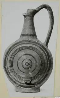 Painted pottery jug with a single loop handle and concentric rings on its rounded body