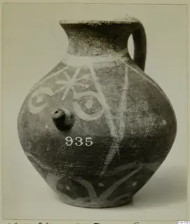 Painted pottery jug with a strap handle, white decoration on a dark surface