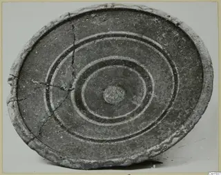 Shallow bowl seen from above, with concentric dark and pale bands around a central boss