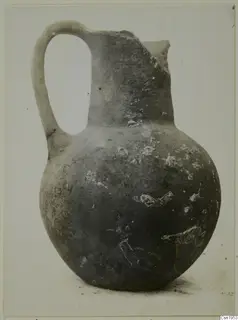Pottery jug with a tall neck, a broken rim and a loop handle.