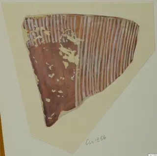 Pottery sherd with a reddish-brown surface and white vertical stripes, shown on a cream card mount