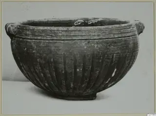 Pottery Black Slip I-VI bowl with two small handles at the rim and vertical grooves on the body