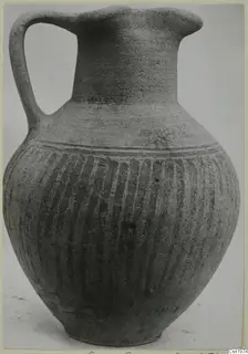 Pottery Black Slip Ware jug with one strap handle and vertical grooves on the body