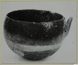 Pottery Reserved Ware bowl from Vounous with a single handle, photographed and mounted on a card.
