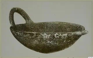 Pottery Red Polished IV: a bowl with a single loop handle, shown in side profile against a plain background.
