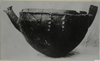 Red Polished III bowl with a spout-like projection on the left and a handle-like projection on the right, seen from the side.