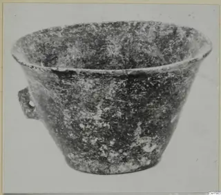 Bowl with a flared rim and a small handle with a hole on one side, seen from the side