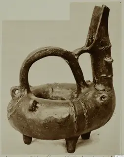Red Polished III pottery amphora from Vounous, with a tall spout, strap handle and three feet, photographed against a plain background