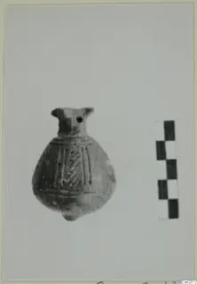 Small globular pottery vessel with a short neck, rim projections and incised lines on the body, beside a scale bar.