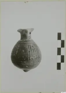 Small pottery vessel with a narrow neck and incised lines on the body, shown beside a scale bar