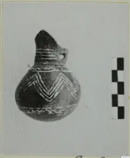 Pottery vessel with a narrow neck, side loop handle and light chevron bands, beside a checkered scale bar.