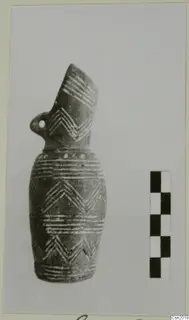 Pottery vessel with a tall spout, loop handle and white painted chevron and band decoration, shown beside a scale bar.