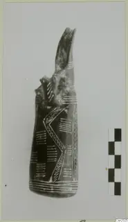 Dark pottery vessel with white incised chevron and hatched decoration and a tall curved projection on top