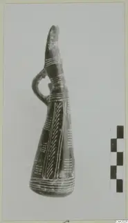 Dark pottery vessel with a tall neck, side loop handle and white painted bands and herringbone pattern.