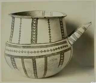White Slip ware vessel with a tubular spout and dark brown painted bands and lattice panels